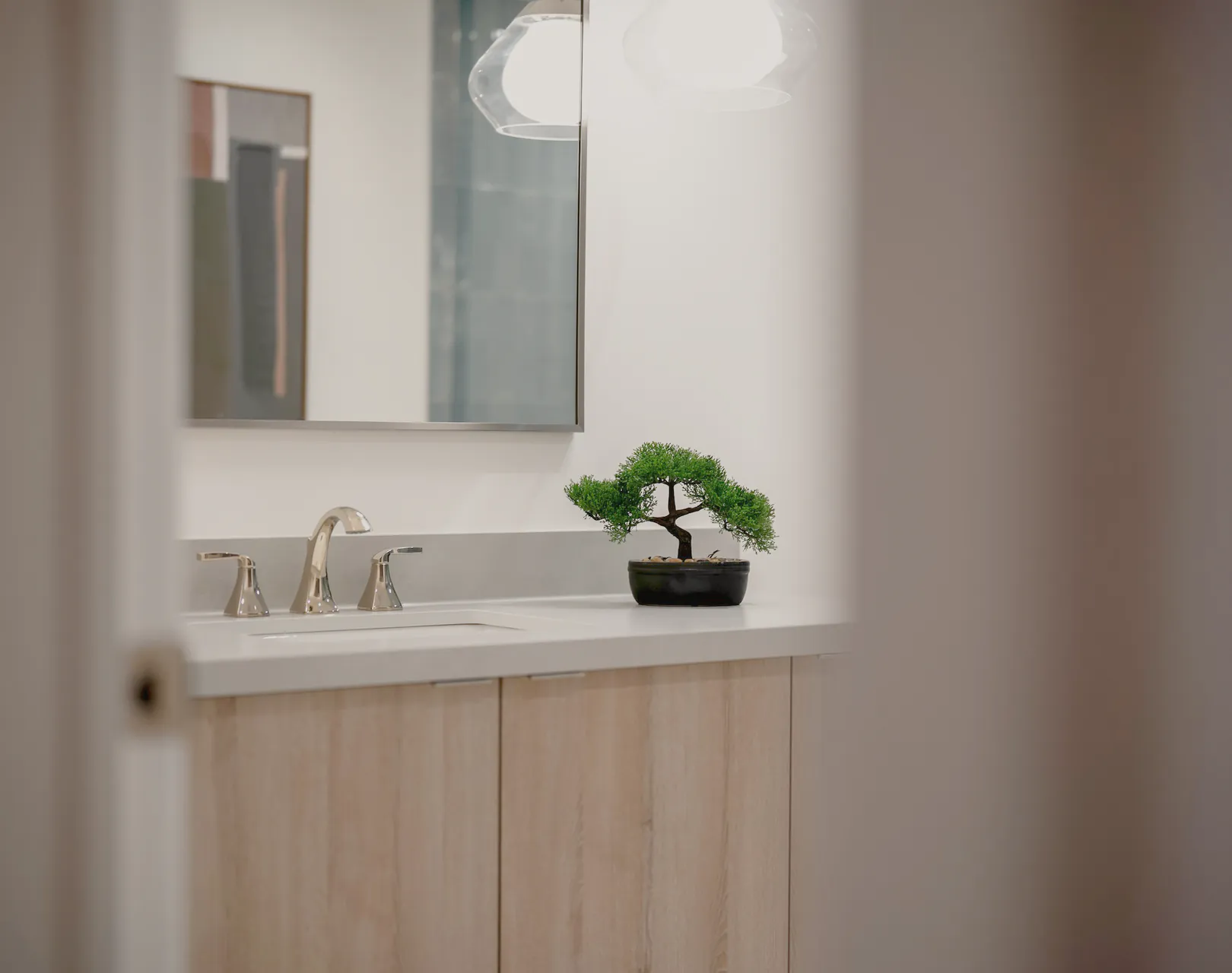 A vanity and brass mixer seen through a doorway