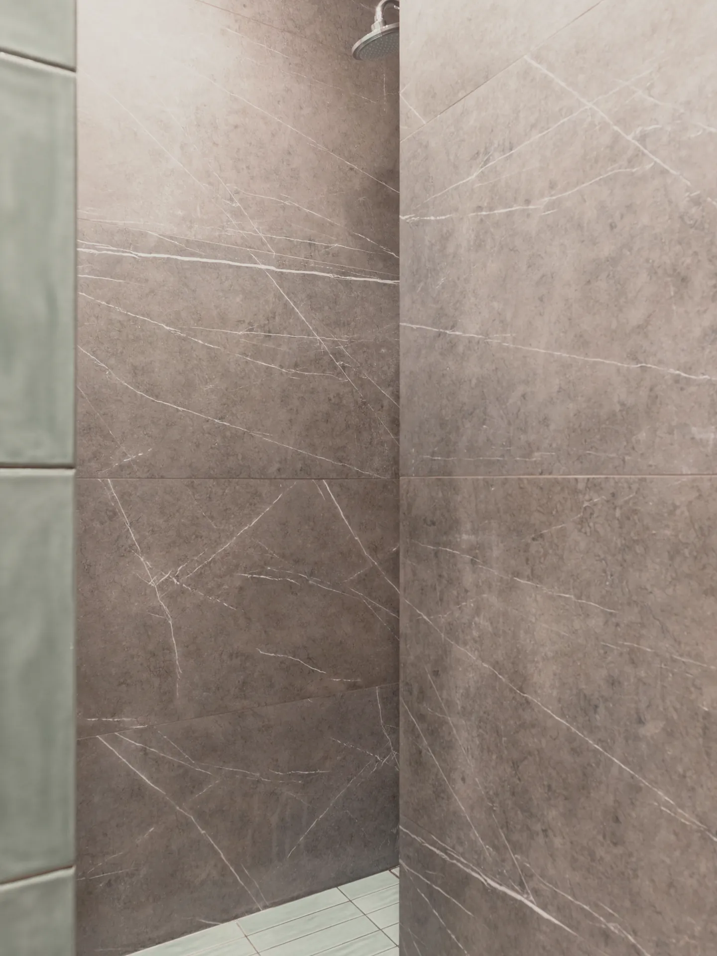 The shower recess in grey stone and green tile