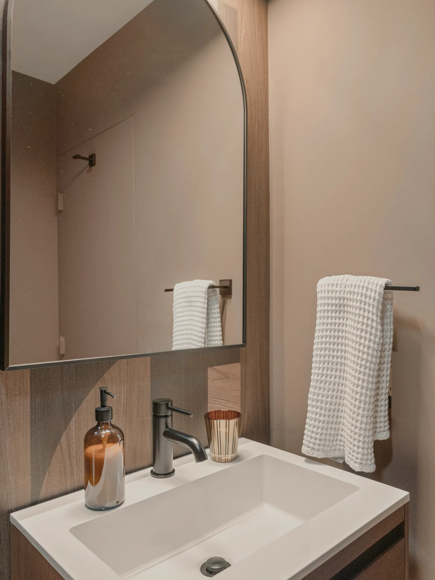 A basin under an arched mirror in the main bathroom