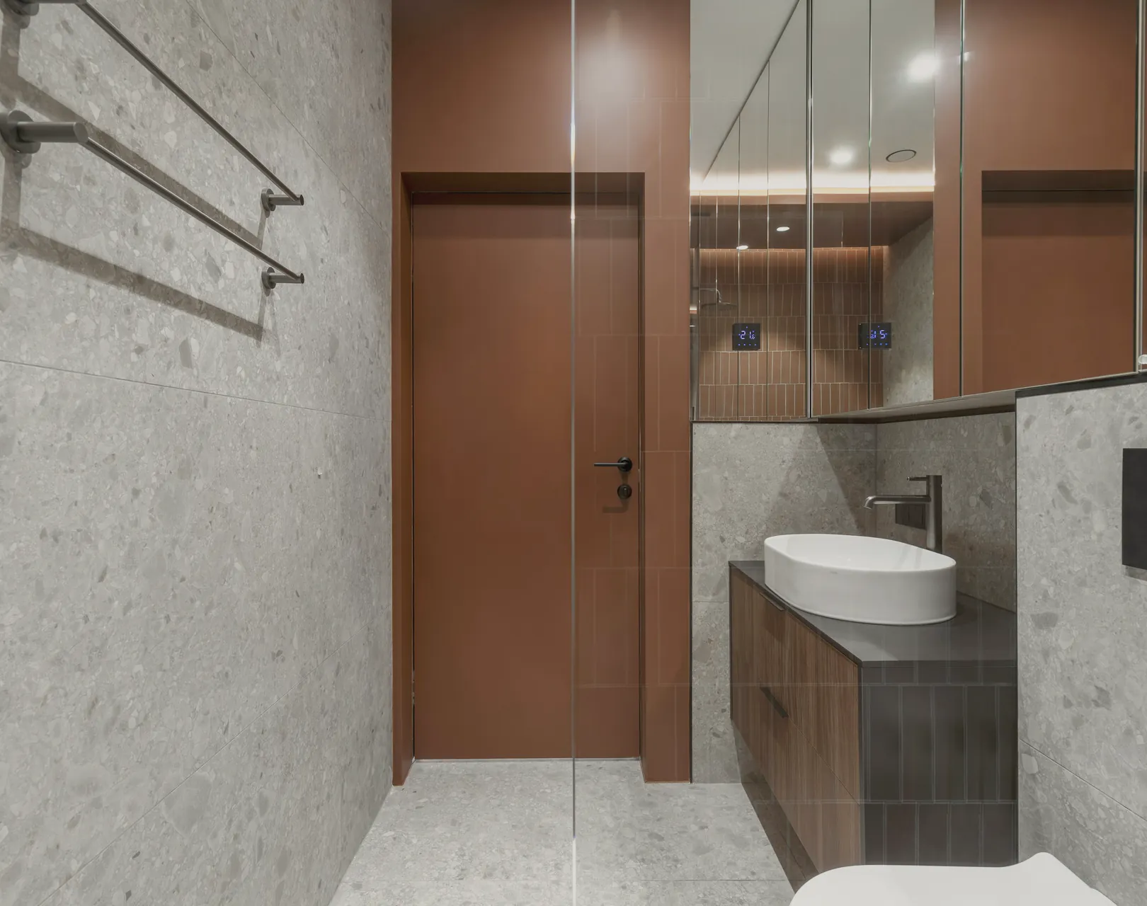 A basin and mirror over walnut cabinetry