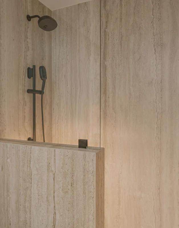 A travertine shower with a hand shower
