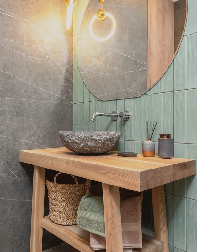 A stone basin and wall mixer on green tile
