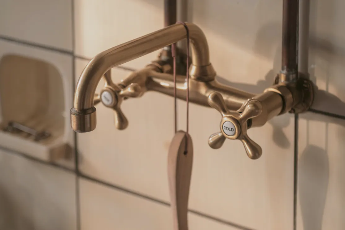 A brass wall mixer set level over the basin