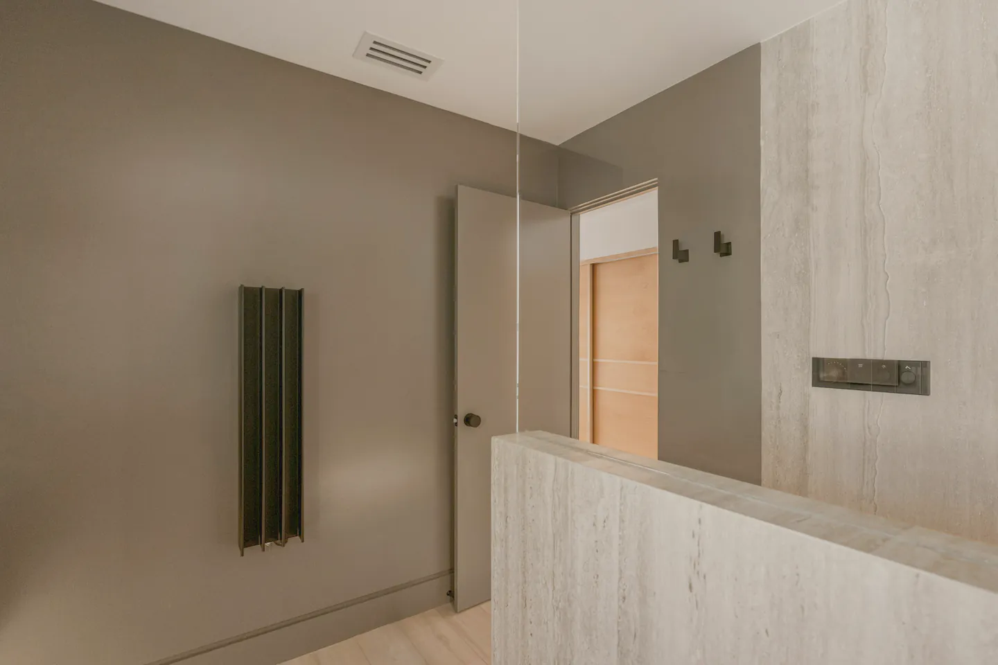 The ensuite’s dark walls, towel rail and shower in evening light