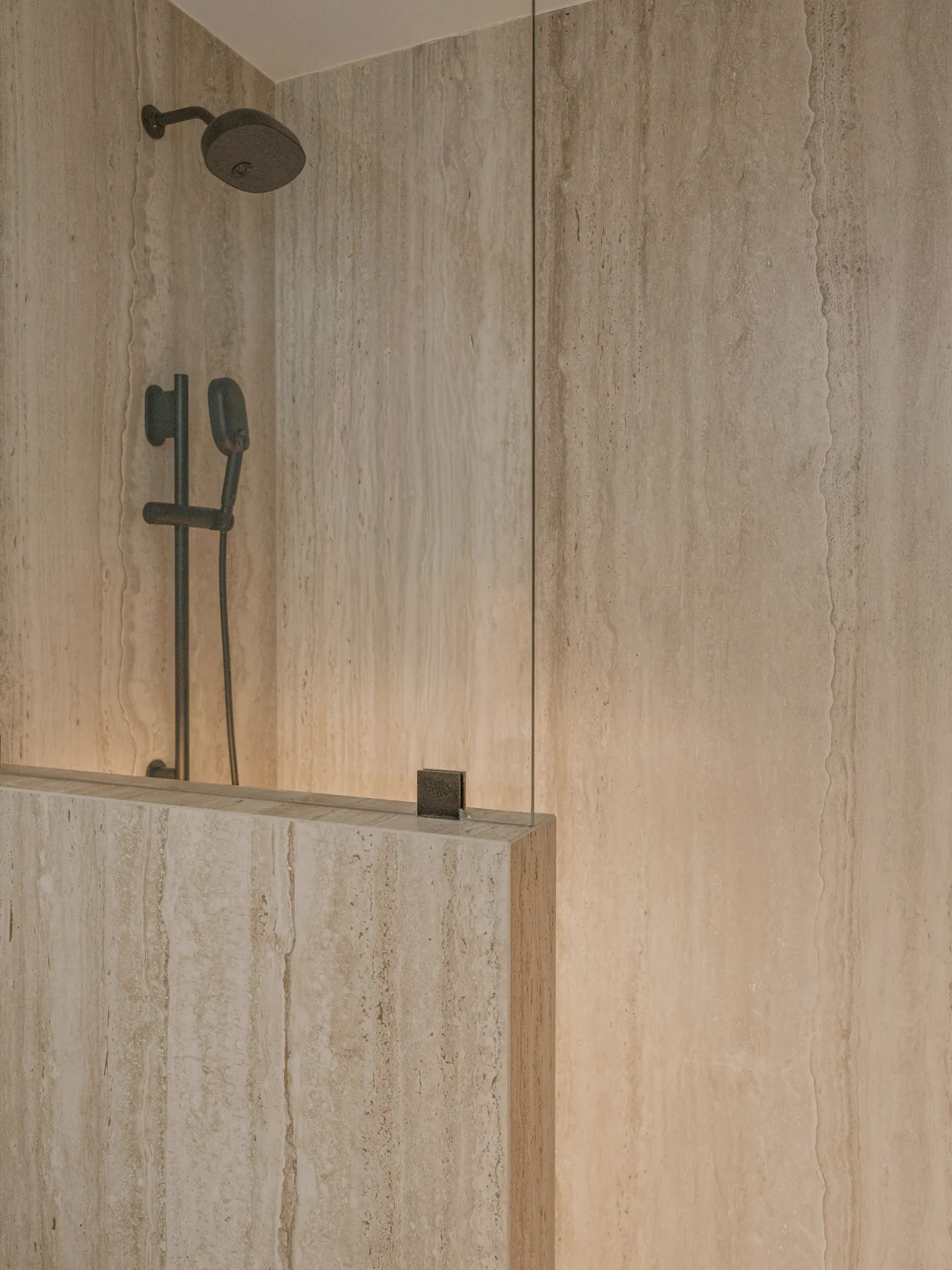 A hand shower and rail on the travertine wall