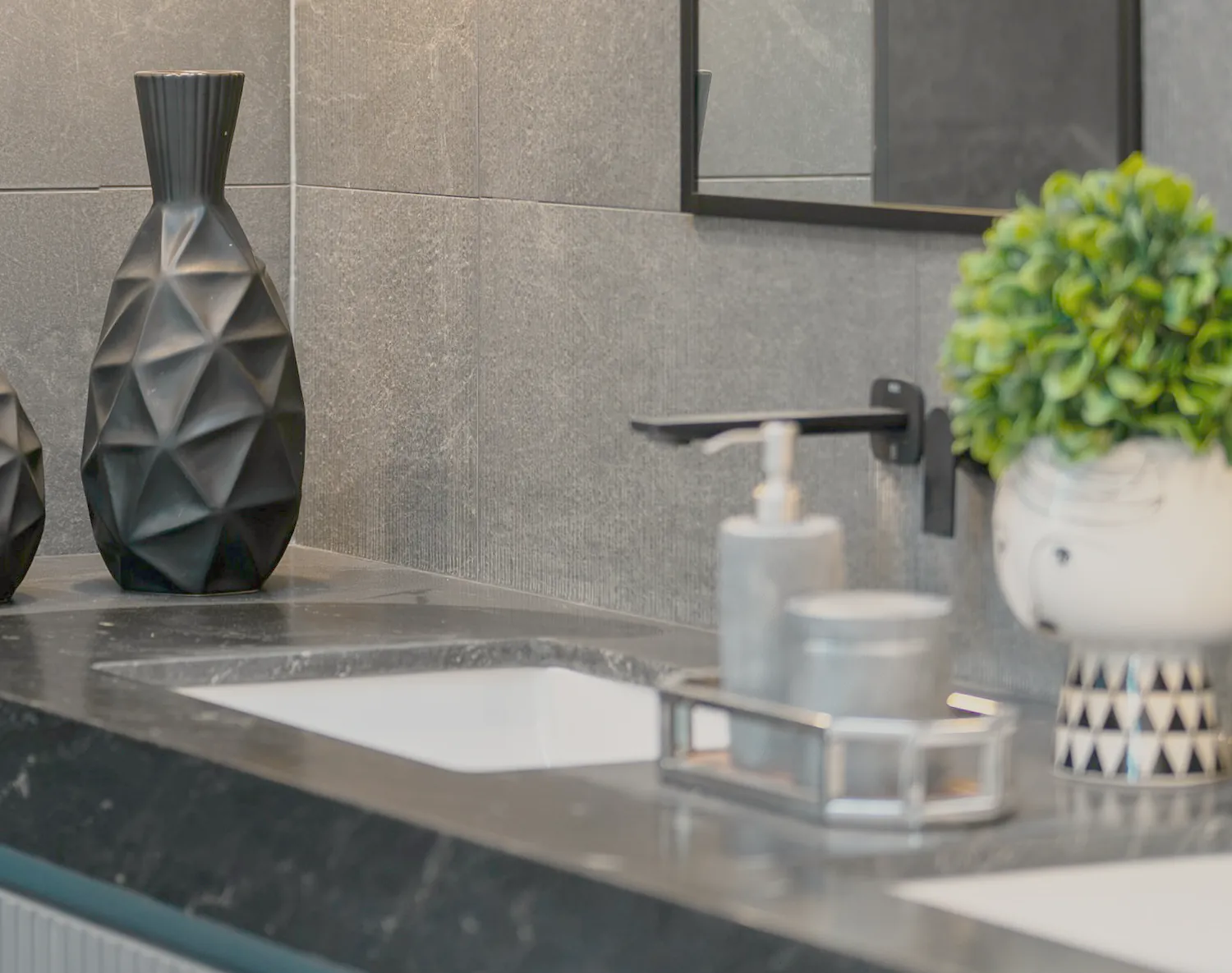 The dark stone vanity, its basin and black mixer