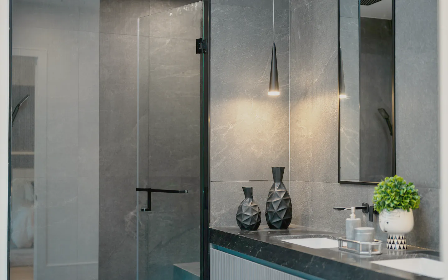 An ensuite in dark stone with a frameless shower and a stone vanity